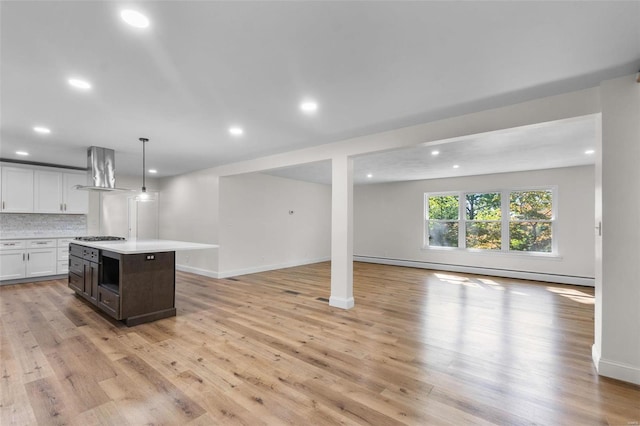 kitchen with a center island, extractor fan, hanging light fixtures, white cabinetry, and light hardwood / wood-style flooring