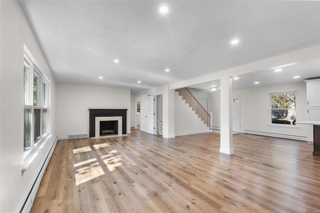 unfurnished living room featuring a baseboard radiator and light hardwood / wood-style flooring