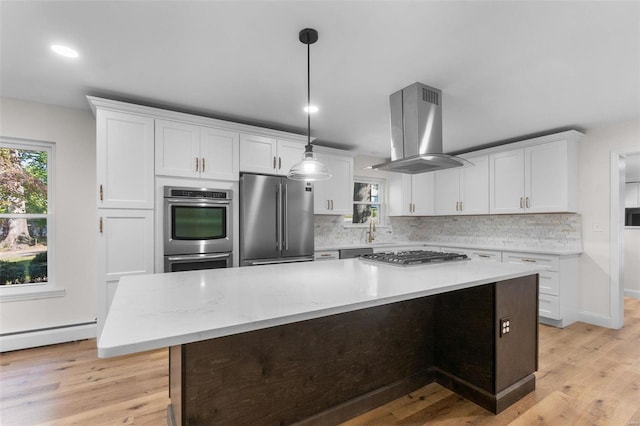 kitchen featuring stainless steel appliances, light hardwood / wood-style floors, decorative light fixtures, and island range hood