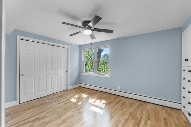 unfurnished bedroom featuring ceiling fan, a closet, a baseboard heating unit, and light hardwood / wood-style flooring