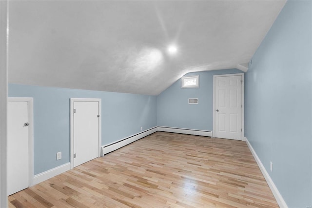 additional living space with baseboard heating, vaulted ceiling, and light hardwood / wood-style flooring