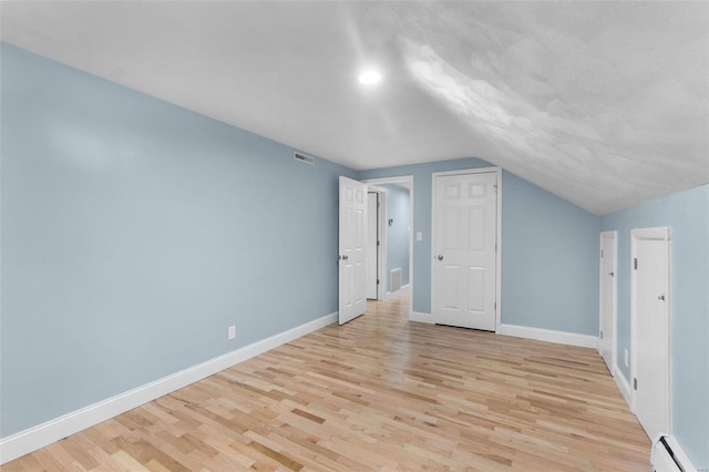 bonus room featuring lofted ceiling, a baseboard heating unit, and light wood-type flooring