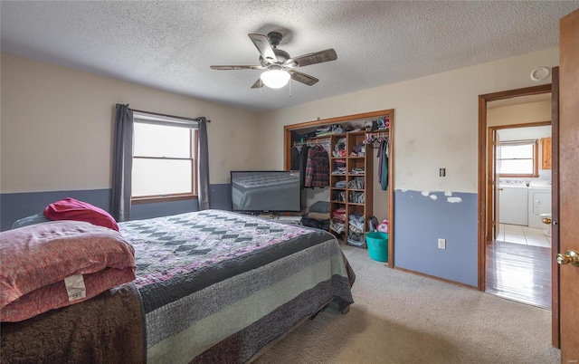 carpeted bedroom featuring ceiling fan, separate washer and dryer, a textured ceiling, and a closet