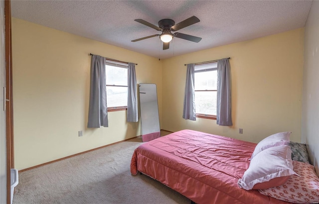 carpeted bedroom featuring ceiling fan and a textured ceiling