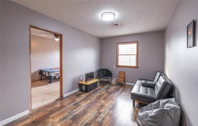 sitting room featuring ceiling fan, dark hardwood / wood-style floors, and a textured ceiling