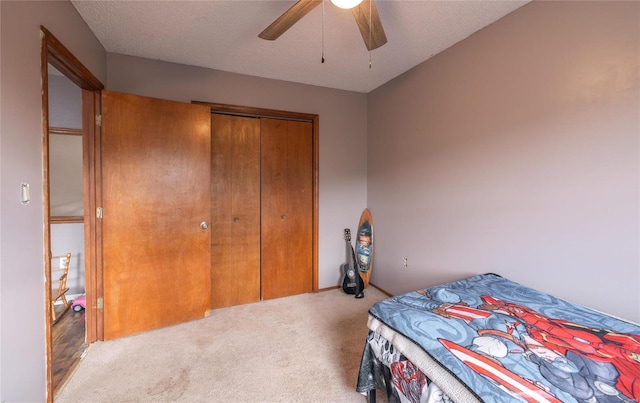 carpeted bedroom with ceiling fan, a closet, and a textured ceiling