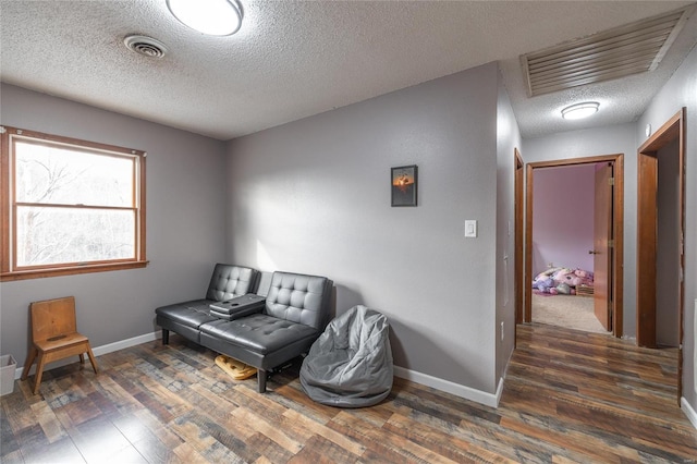 living area with a textured ceiling and dark hardwood / wood-style floors