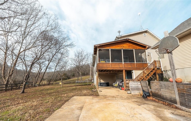 rear view of house with a patio, a trampoline, and a sunroom