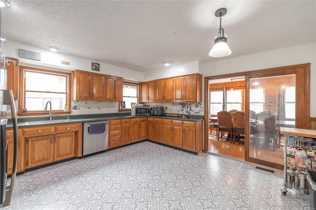 kitchen with dishwasher, sink, hanging light fixtures, a textured ceiling, and tasteful backsplash