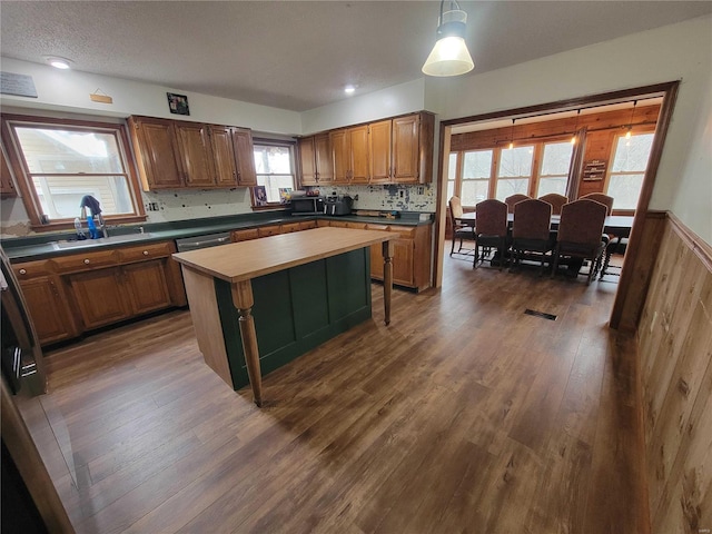 kitchen featuring black microwave, dark wood-style flooring, a sink, brown cabinets, and tasteful backsplash