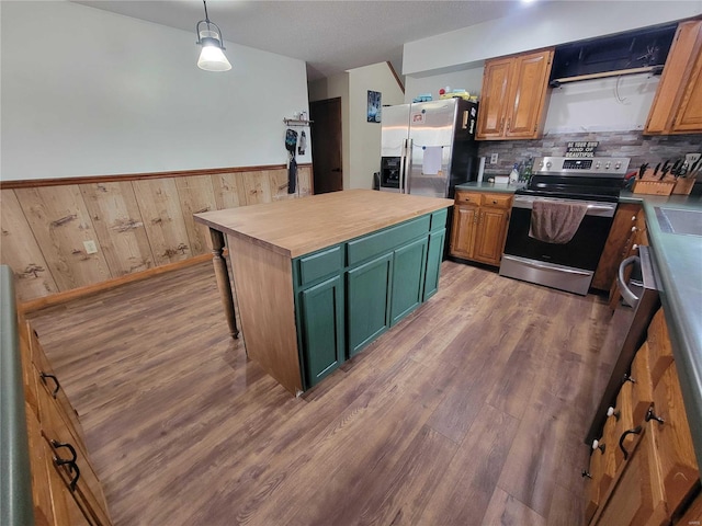 kitchen featuring light wood finished floors, tasteful backsplash, appliances with stainless steel finishes, and wainscoting