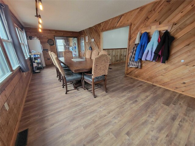 dining area featuring wood finished floors, visible vents, and wooden walls