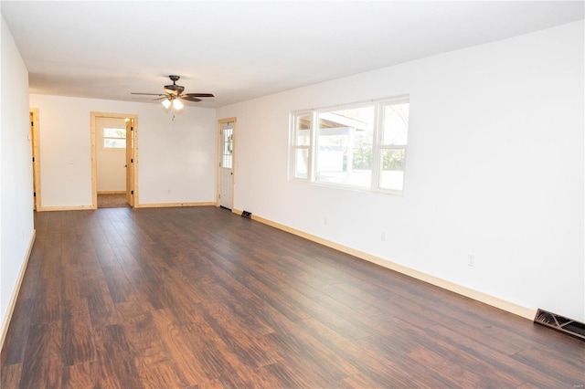 empty room featuring dark wood-type flooring, ceiling fan, and a healthy amount of sunlight