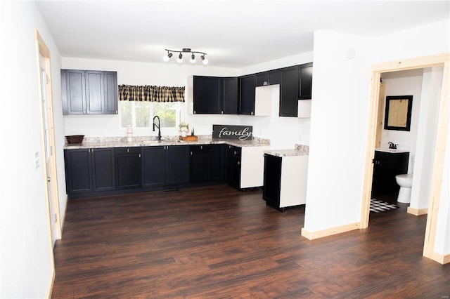 kitchen with light stone countertops, dark hardwood / wood-style floors, and sink