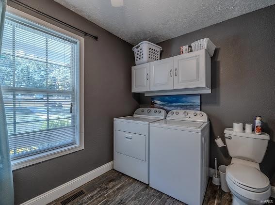 laundry area featuring a textured ceiling, washing machine and clothes dryer, and dark hardwood / wood-style flooring