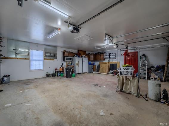 garage with a garage door opener and white refrigerator