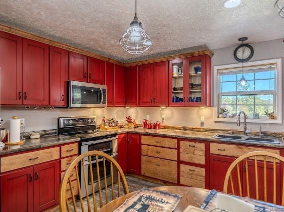 kitchen with appliances with stainless steel finishes, hanging light fixtures, sink, and a textured ceiling