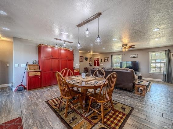 dining room with wood-type flooring, ceiling fan, and a textured ceiling