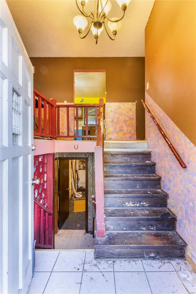 stairway with a textured ceiling, a chandelier, and tile patterned flooring