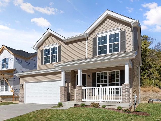 view of front of home featuring a garage, a front yard, and covered porch