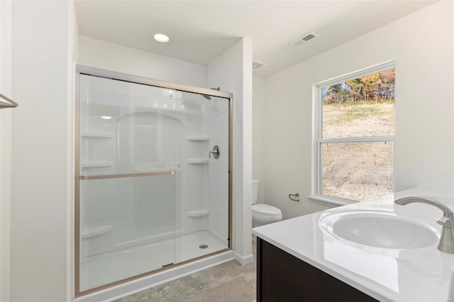 bathroom with a shower with door, vanity, and toilet