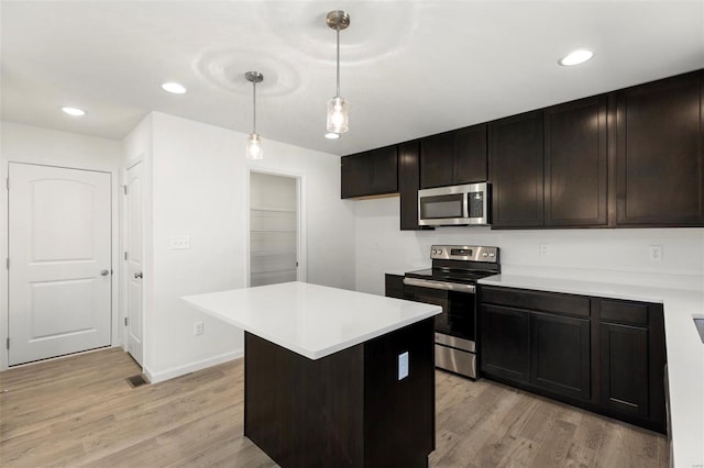 kitchen featuring stainless steel appliances, hanging light fixtures, light hardwood / wood-style flooring, and a center island