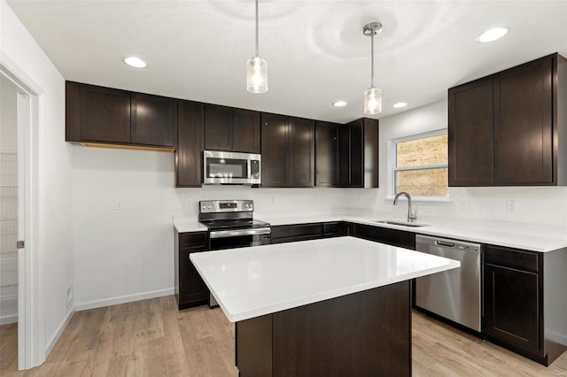 kitchen featuring hanging light fixtures, sink, light hardwood / wood-style flooring, stainless steel appliances, and a center island