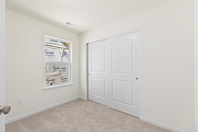 unfurnished bedroom featuring a closet and light colored carpet