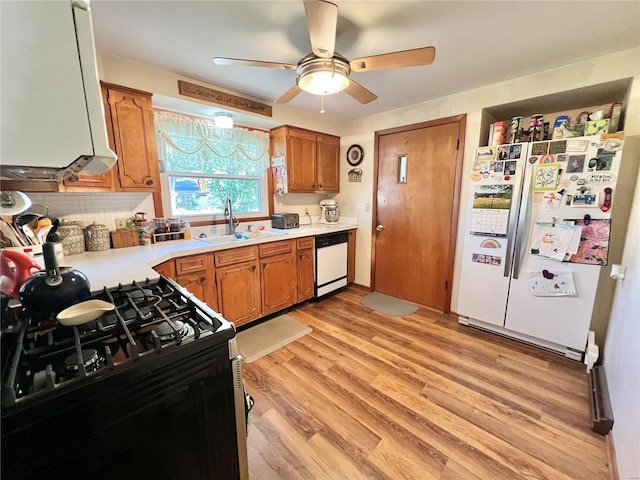 kitchen featuring white appliances, backsplash, sink, ceiling fan, and light wood-type flooring