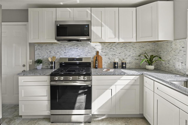 kitchen with light stone counters, stainless steel appliances, tasteful backsplash, and white cabinets