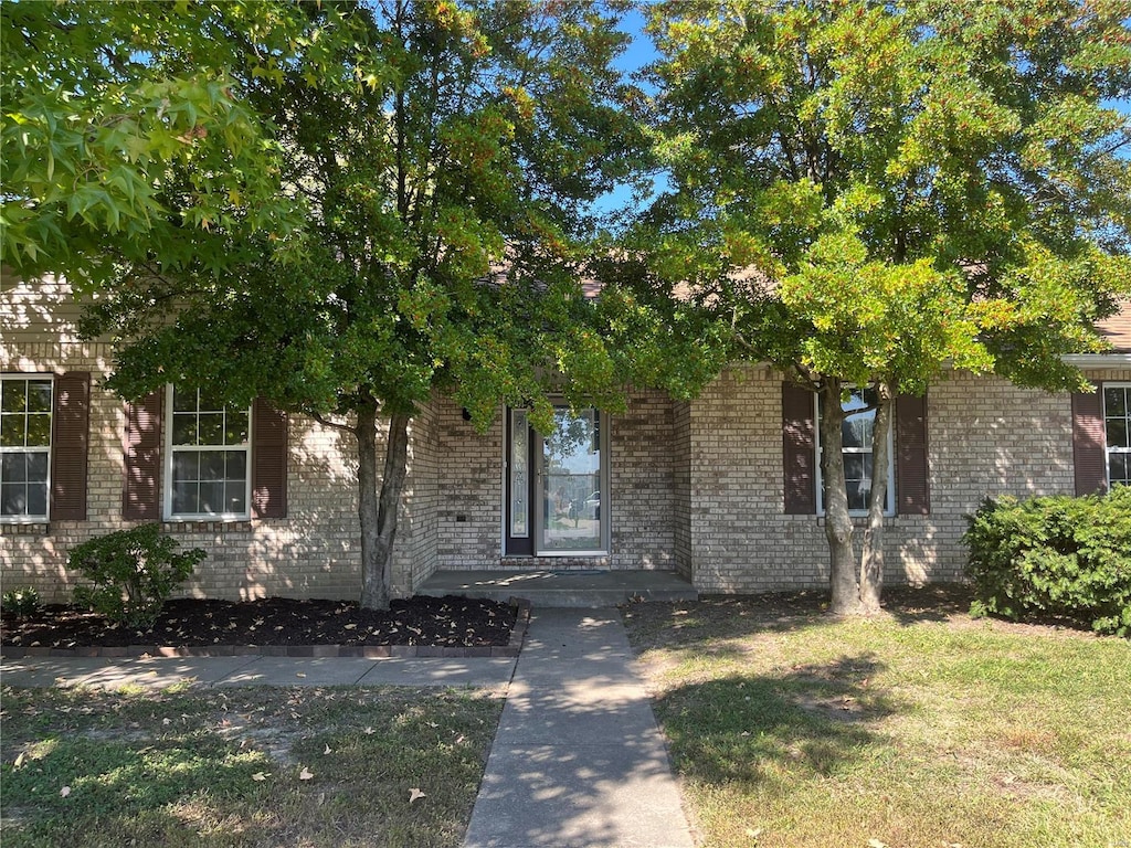 view of property hidden behind natural elements featuring a front yard