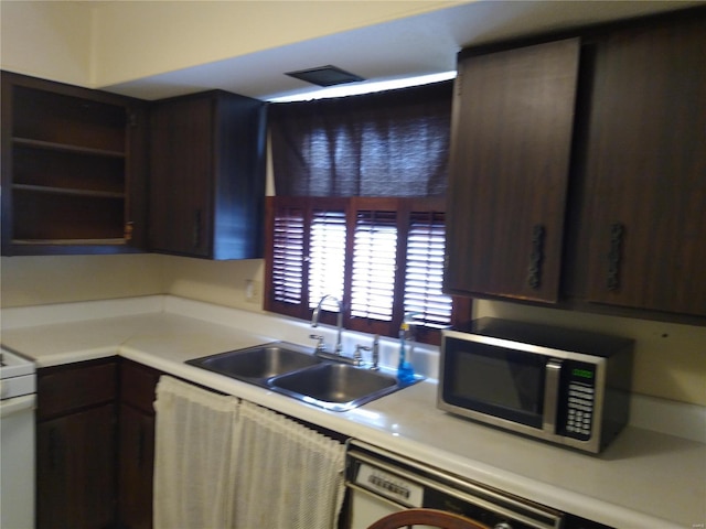 kitchen featuring dark brown cabinets, white stove, sink, and washer / dryer