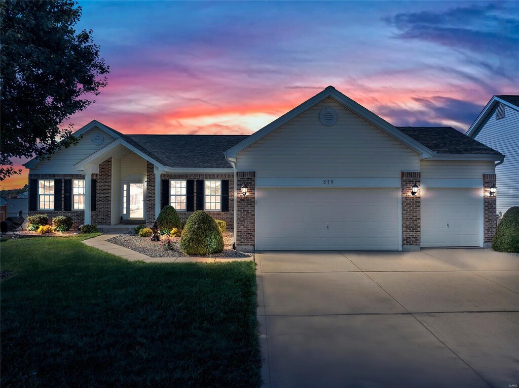 single story home with a garage and a lawn