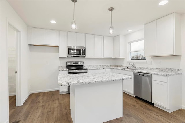 kitchen featuring a kitchen island, hardwood / wood-style floors, white cabinetry, appliances with stainless steel finishes, and decorative light fixtures