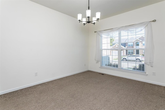 spare room with a chandelier and carpet flooring