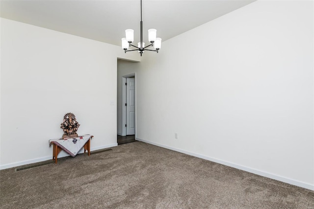 carpeted spare room with a notable chandelier