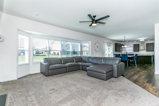 living room featuring dark wood-type flooring and ceiling fan with notable chandelier