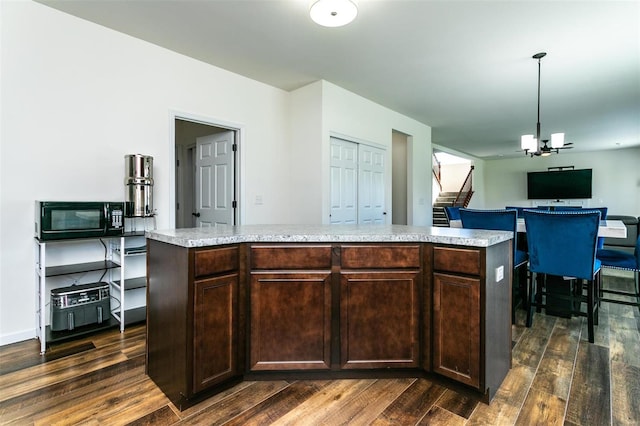 kitchen with a kitchen island, dark brown cabinets, decorative light fixtures, and dark hardwood / wood-style flooring