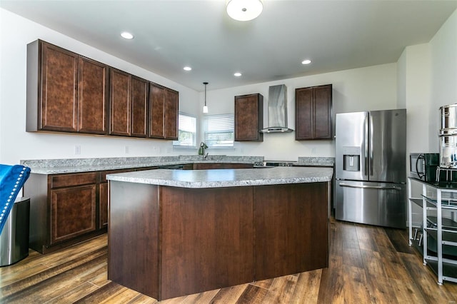 kitchen featuring appliances with stainless steel finishes, dark brown cabinets, dark wood-type flooring, and wall chimney range hood