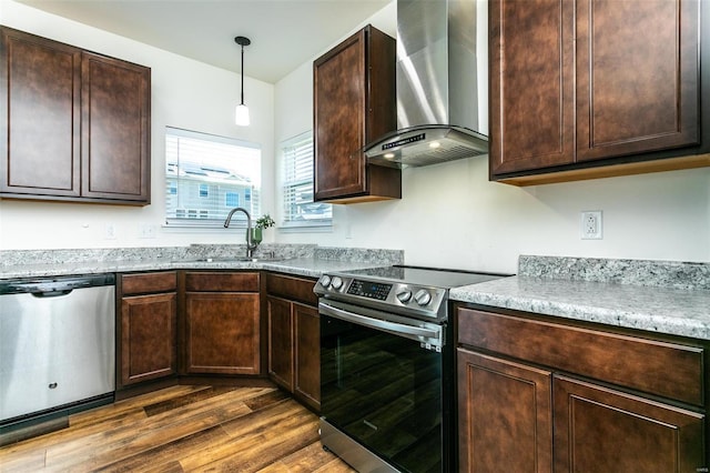 kitchen featuring sink, stainless steel appliances, wall chimney exhaust hood, decorative light fixtures, and dark hardwood / wood-style floors