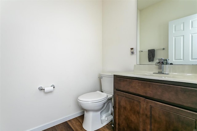 bathroom with toilet, vanity, and wood-type flooring