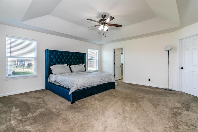 carpeted bedroom featuring a raised ceiling and ceiling fan