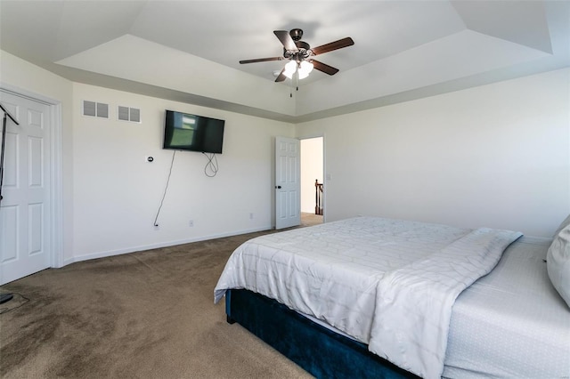 carpeted bedroom featuring ceiling fan and a raised ceiling