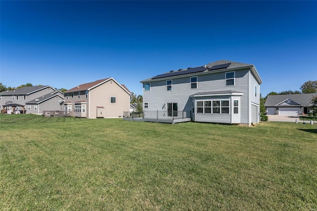 rear view of property featuring a yard, solar panels, and a sunroom