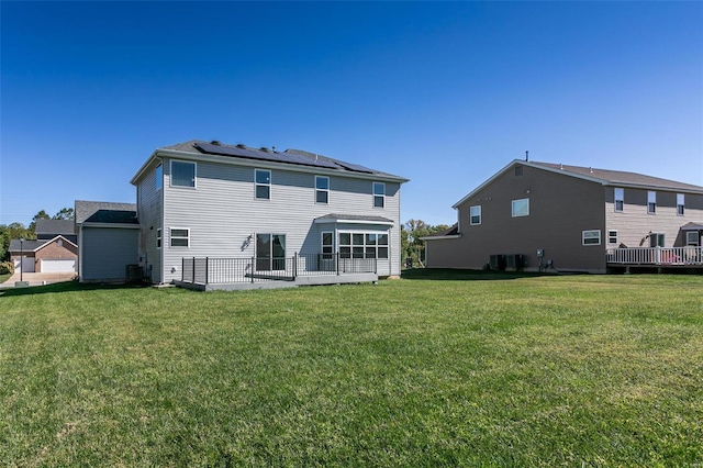 back of property with a yard and solar panels