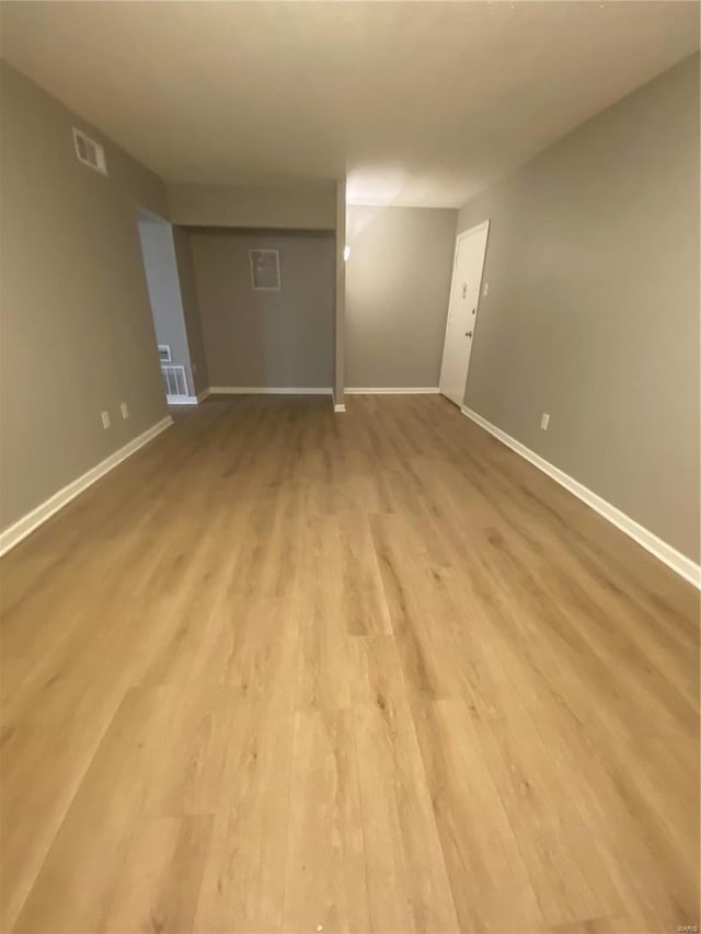 spare room with light wood finished floors, visible vents, and baseboards