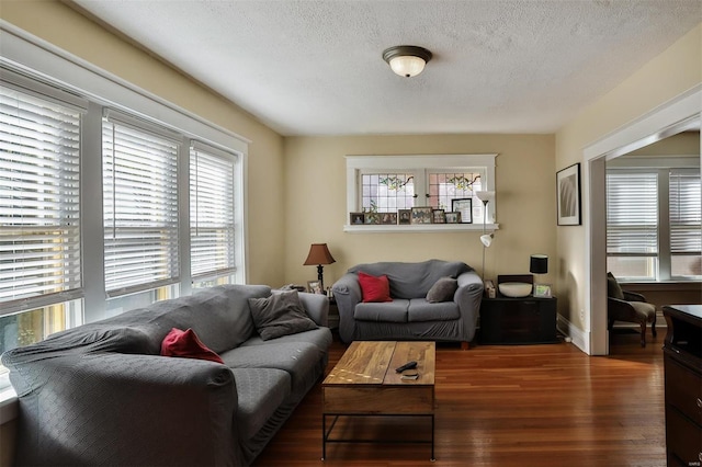 living room with a textured ceiling, a healthy amount of sunlight, and dark wood-type flooring