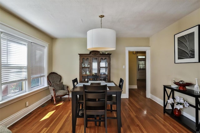 dining room featuring a textured ceiling and dark hardwood / wood-style flooring