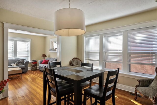 dining area with wood-type flooring and a textured ceiling