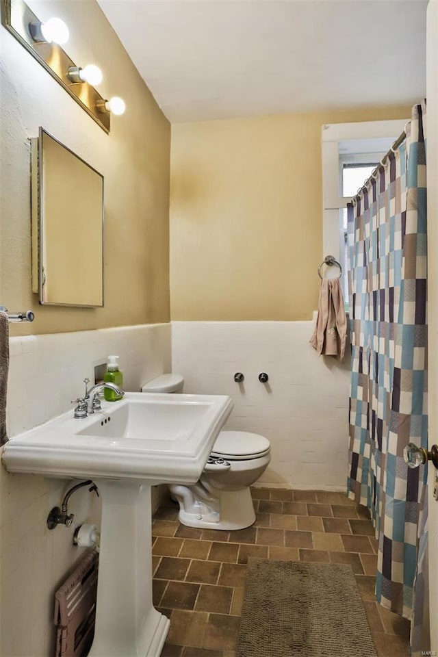 bathroom featuring toilet, tile walls, and curtained shower